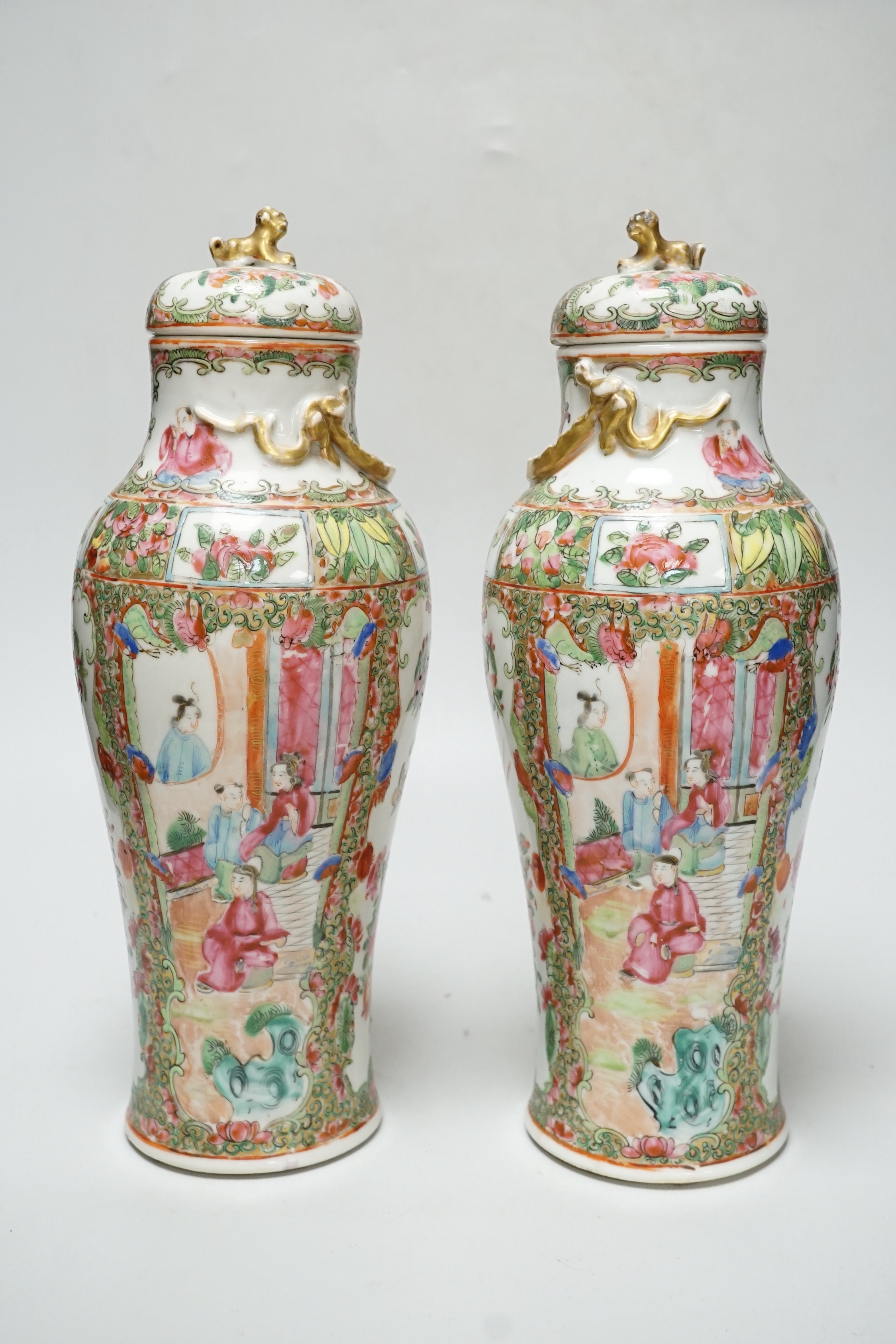 A pair of Chinese famille rose Canton baluster jars and covers with lion dog finials, 32cm high